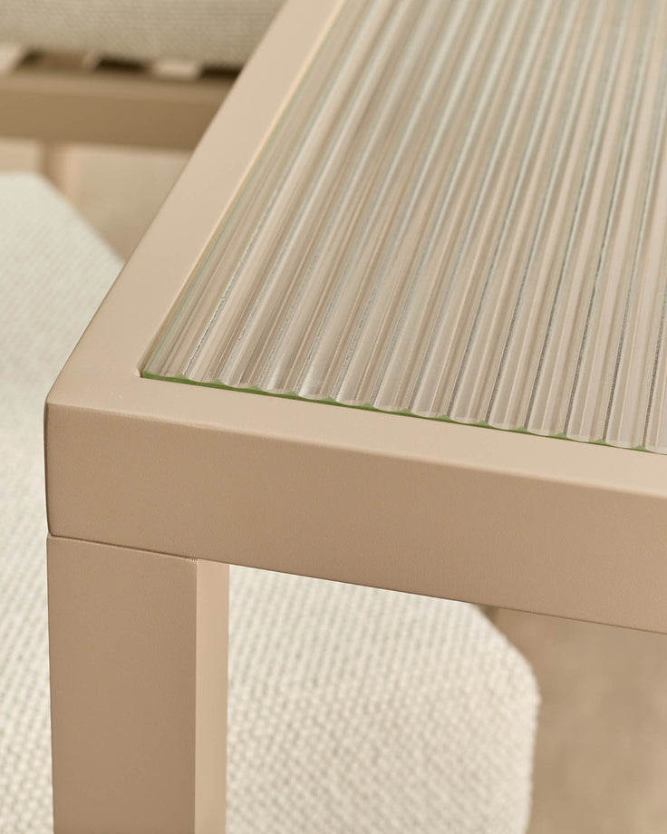 Beige dining table with ribbed glass top and green accent edge detail, angled close-up view.