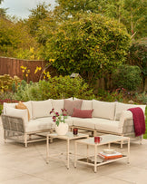 Minori natural garden corner bench and coffee table set with cream cushions on outdoor patio, styled with accessories.
