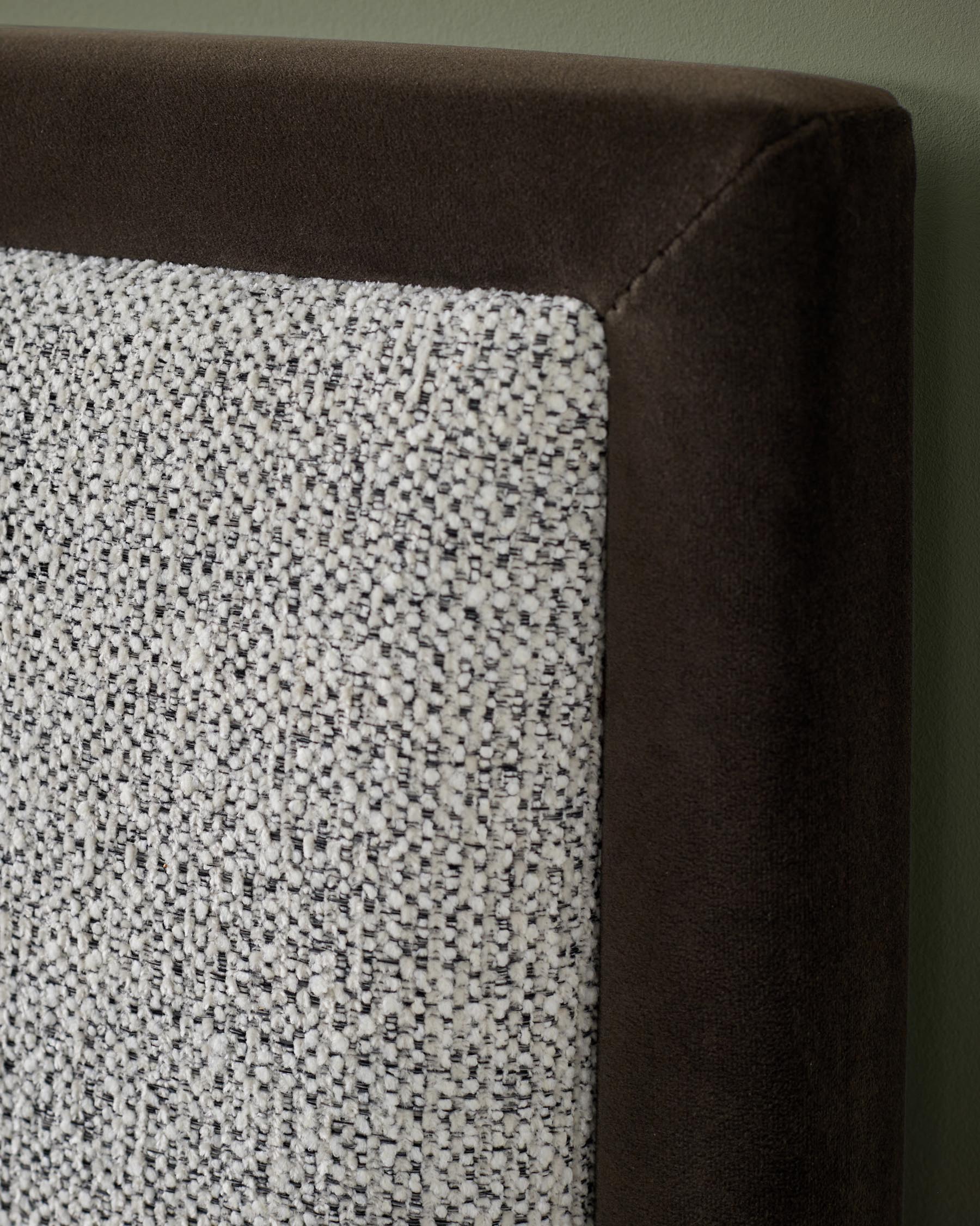 Close-up of a bed headboard with a dark brown velvet frame and a textured fabric panel.