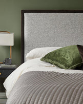 Bedroom featuring upholstered headboard, bedside table with lamp, and olive green wall.