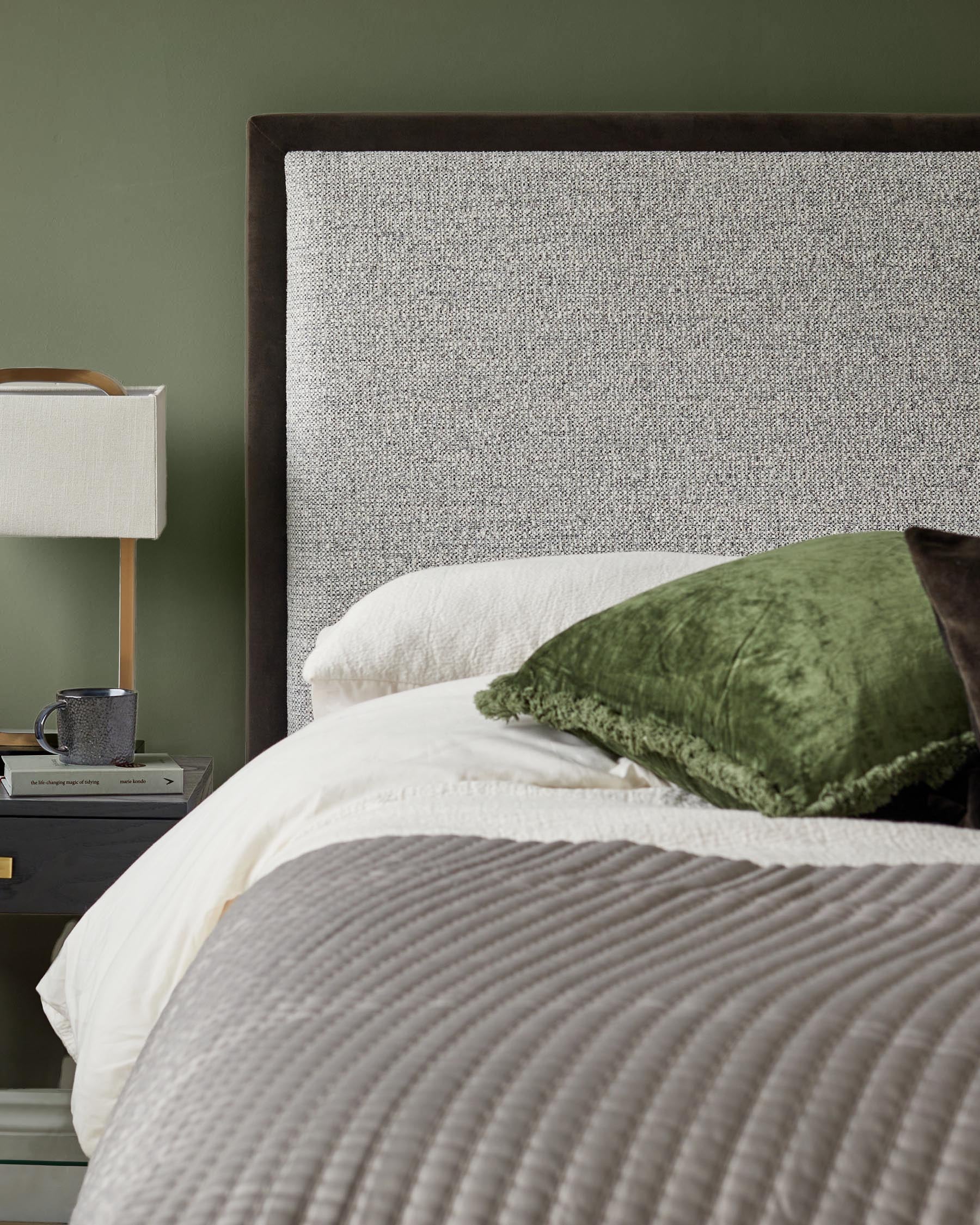 Bedroom featuring upholstered headboard, bedside table with lamp, and olive green wall.