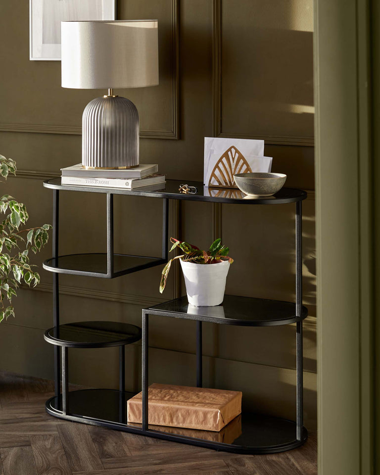 Elegant black multi-tiered shelving unit with sleek curved metal frames and circular and semi-circular glass shelves, featuring decorative objects and a stylish lamp.