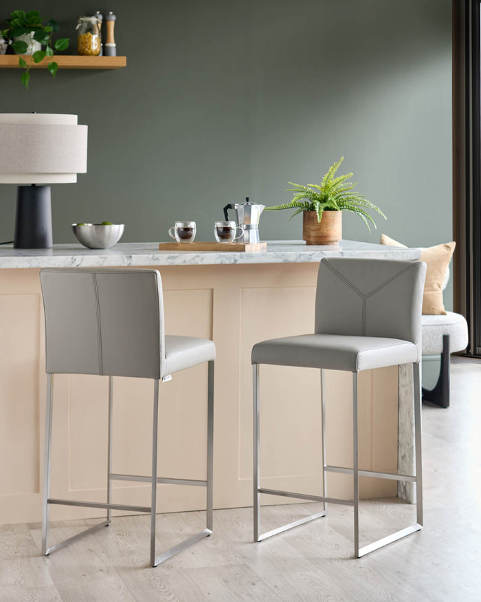 Two grey bar stools with a square seat and a polished metal frame sit by a kitchen island.