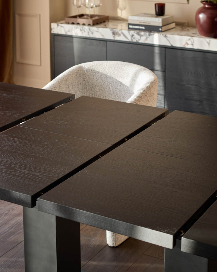 Morgan extending dining table in dark wood with metal base, shown extended with cream upholstered chair.