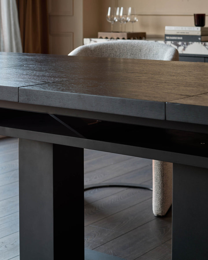 Morgan dining table in dark wood with black base, shown at angle displaying tabletop finish and modern leg design.