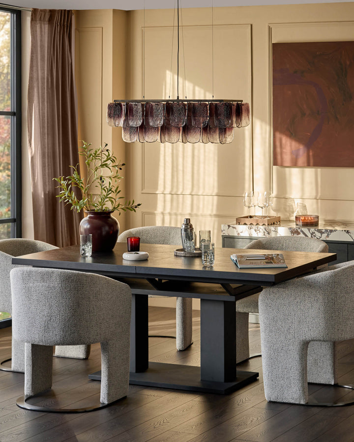 Morgan dark wood dining table with black base, shown with grey upholstered chairs in modern dining room setting.