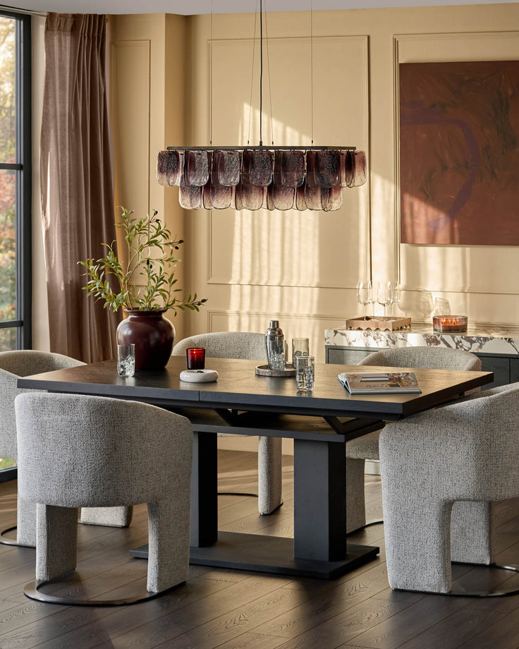 Morgan dark wood dining table with black base, shown with grey upholstered chairs in modern dining room setting.