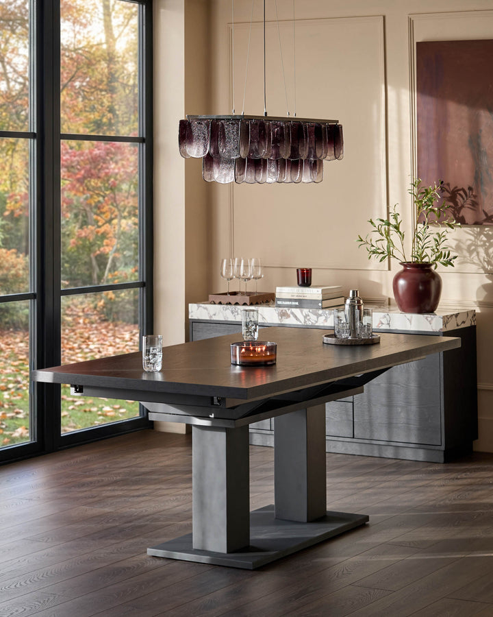 Morgan 8-10 seater dining table in dark wood with extending top and geometric base, shown in modern dining room setting.
