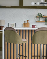 Myra gas lift bar stools in olive green velvet with mocha backs, shown at a striped wood kitchen island.
