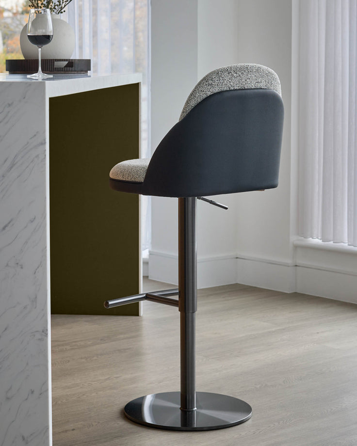Myra gas lift bar stool in grey fabric and black faux leather, shown from side angle with chrome base and footrest.