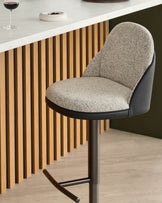 Myra gas lift bar stool with grey fabric seat, black faux leather back, and metal base at counter.
