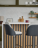 Myra gas lift bar stools in grey fabric and black faux leather, shown at kitchen island with striped wood panel front.