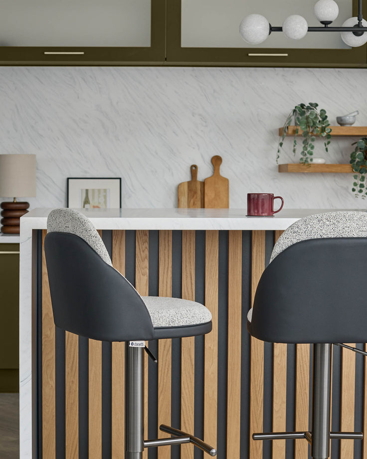 Myra gas lift bar stools in grey fabric and black faux leather, shown at kitchen island with striped wood panel front.