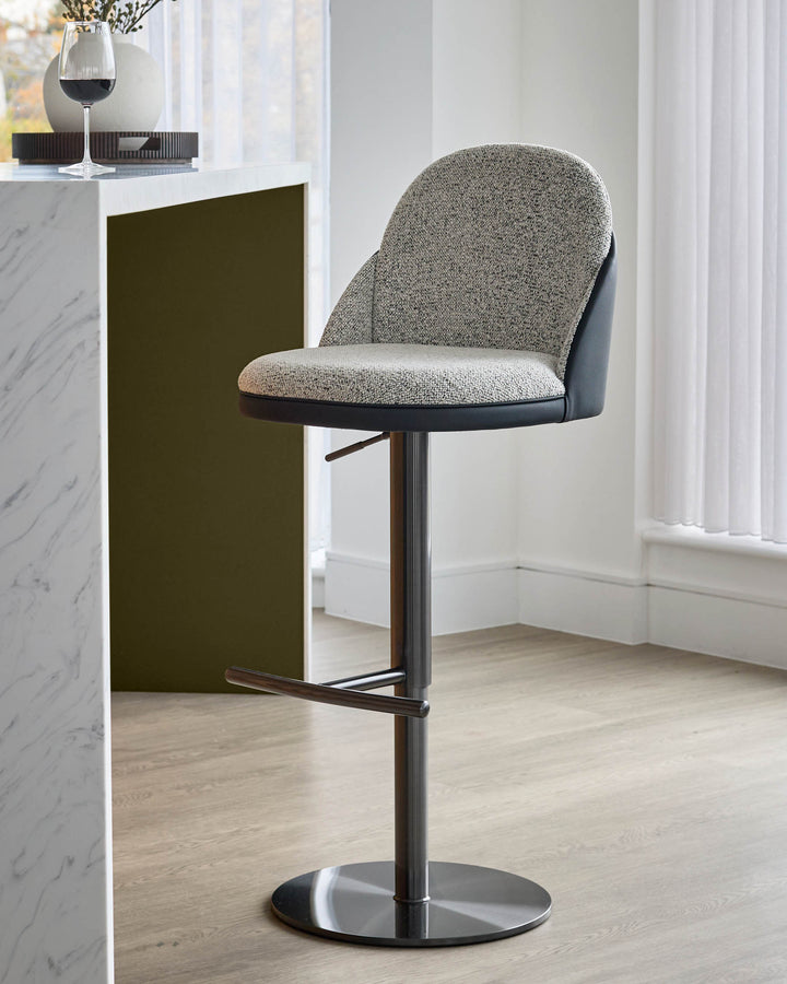Myra gas lift bar stool in grey fabric and black faux leather, shown at an angle with chrome base and footrest.
