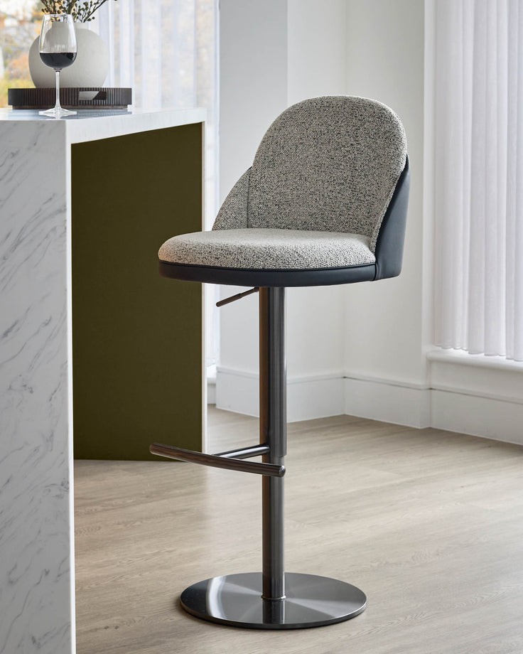Myra gas lift bar stool in grey fabric and black faux leather, shown at an angle with chrome base and footrest.