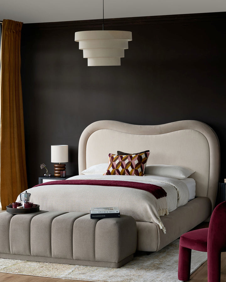 Naomi king-size ottoman bed in champagne velvet with curved headboard and channeled storage base in bedroom setting.