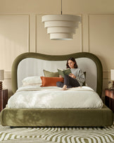 Naomi king-size ottoman bed in olive-green velvet with curved headboard, natural upholstered backrest, shown in bedroom setting.