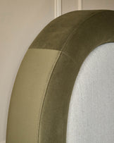 Naomi ottoman bed close-up showing olive green velvet headboard curved edge detail with natural fabric panel insert.