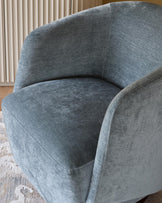 A stylish, blue upholstered armchair with a curved design, perfect for adding a touch of elegance to any living space.