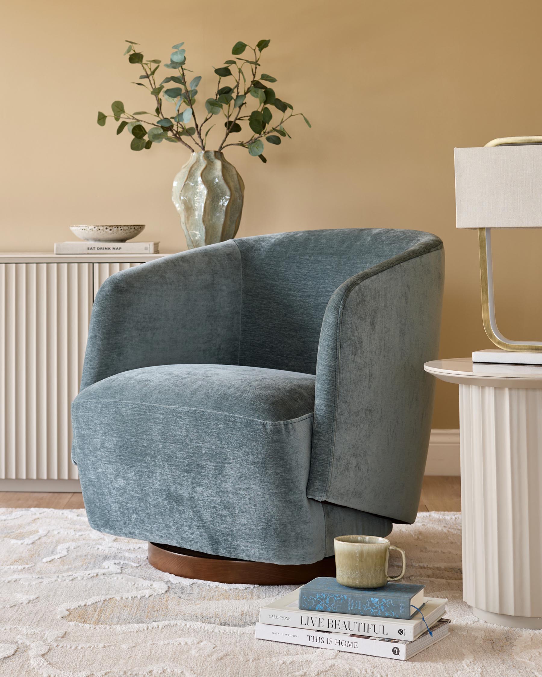 Stylish blue armchair, lamp on side table, and decorative cabinet create a cosy and inviting living space.