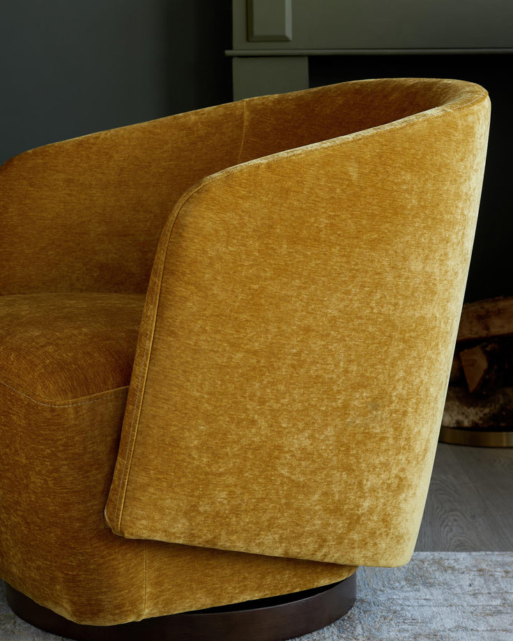 Close-up of a mustard yellow velvet swivel chair, showcasing its curved back and textured fabric.
