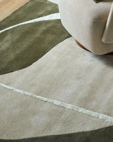 Neo medium textured rug in olive and cream with white stripe detail, shown with beige chair leg.