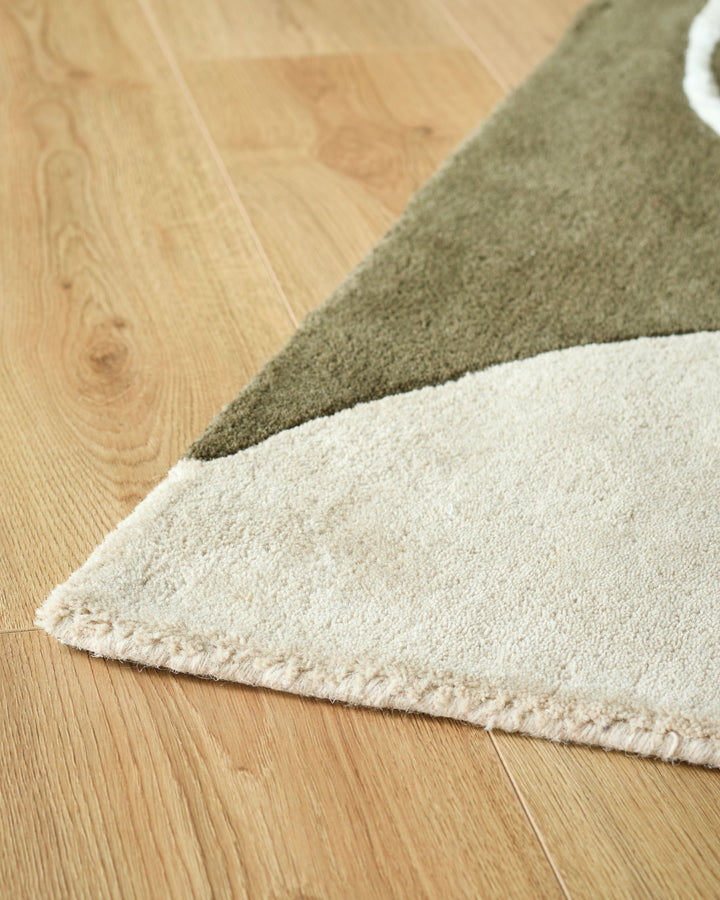 Close-up of a light cream and olive green rug on a wooden floor. Perfect for adding texture and warmth to your living space.
