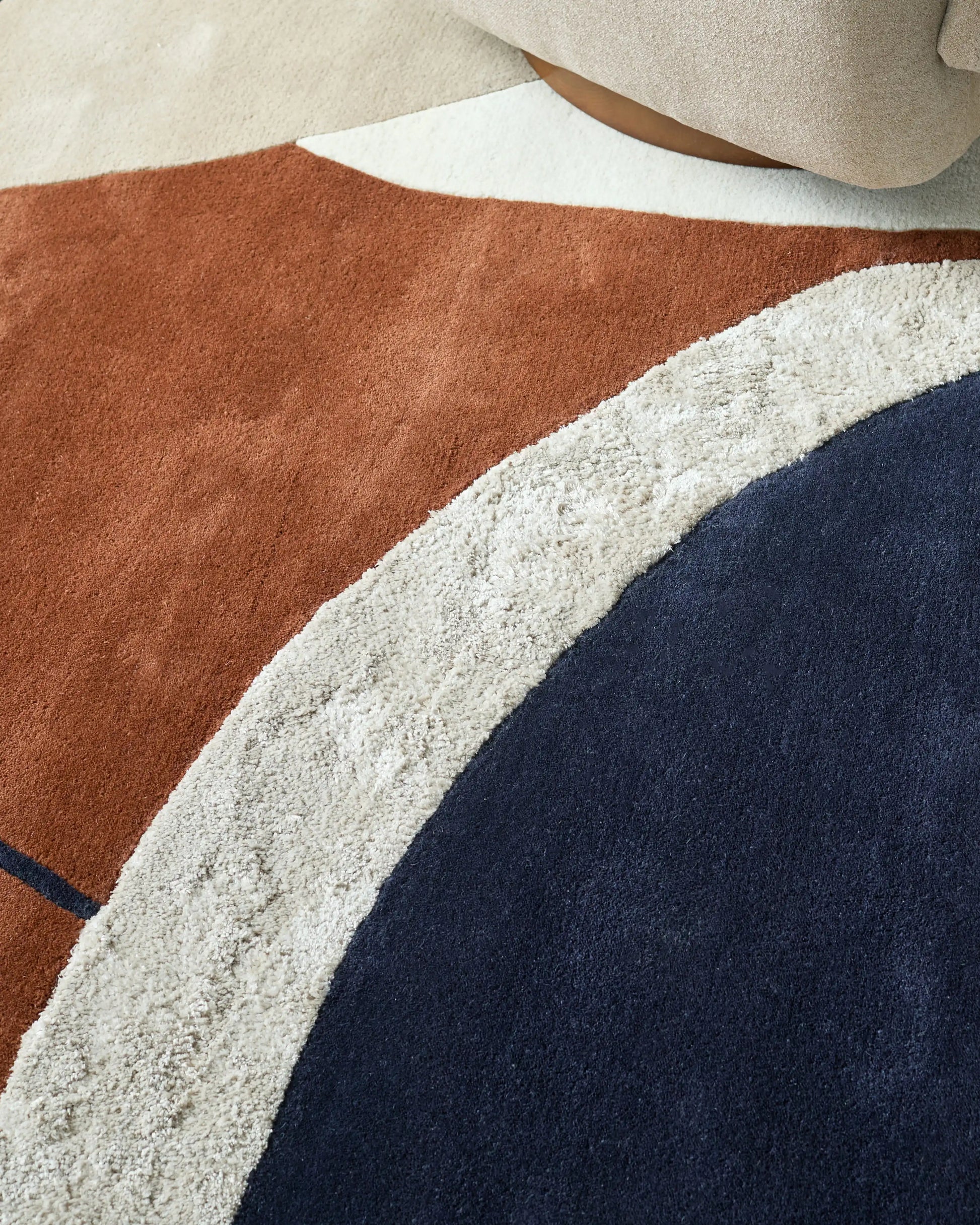 Neo Large Textured Rug in navy, cream, and rust tones with curved geometric design and close-up texture detail.