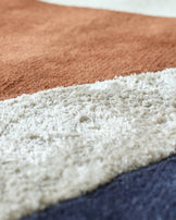 Close-up of a multi-coloured striped rug, featuring beige, cream and navy hues.