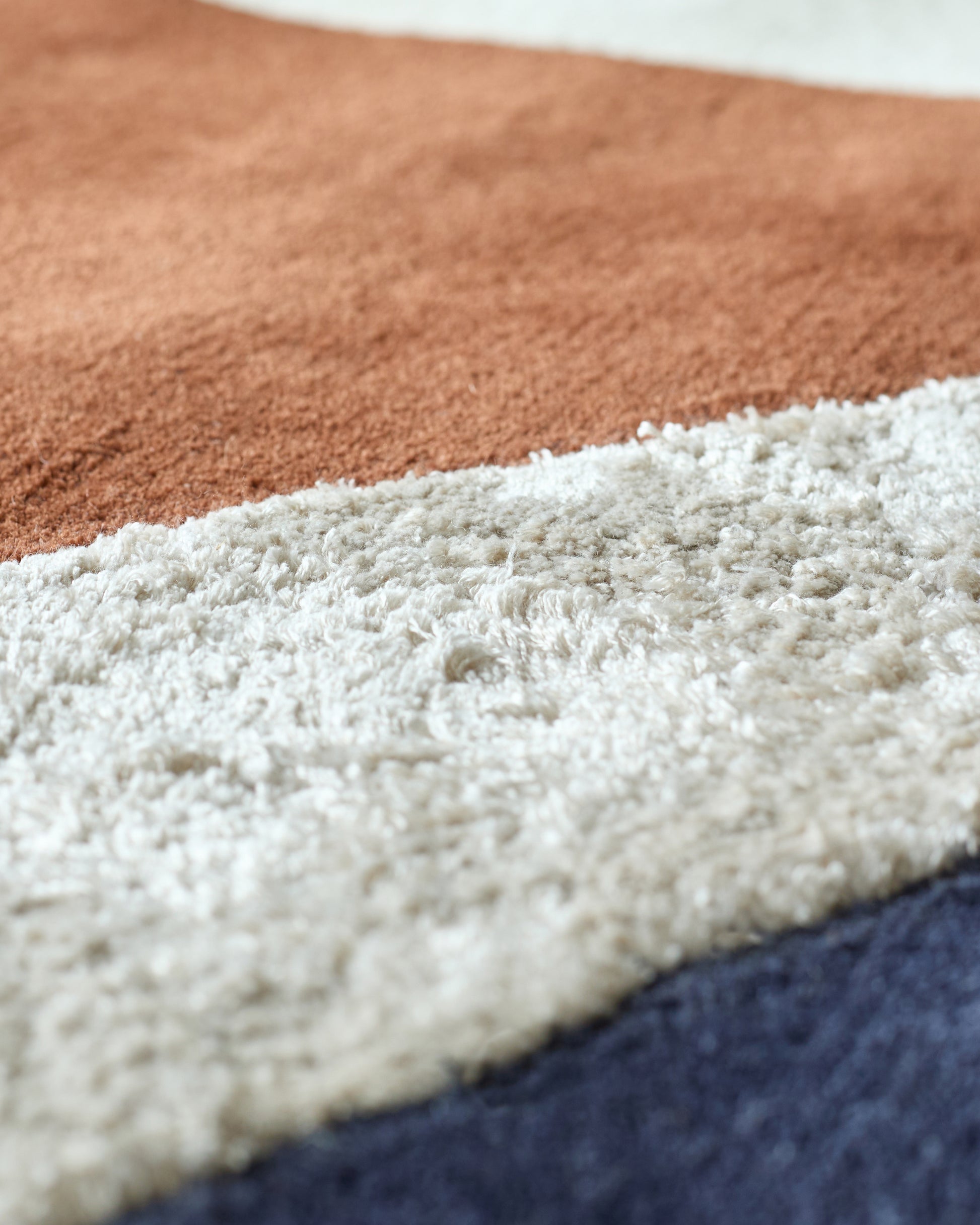 Close-up of a multi-coloured striped rug, featuring beige, cream and navy hues.