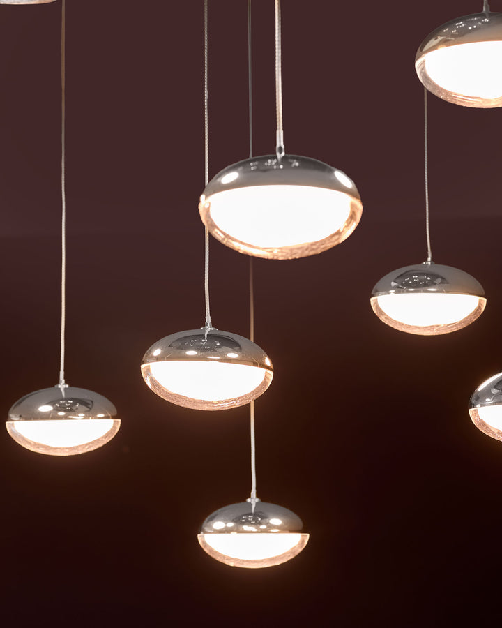 Nina 10 pendant light with chrome and glass construction, featuring multiple disc-shaped fixtures with warm white illumination against dark background.