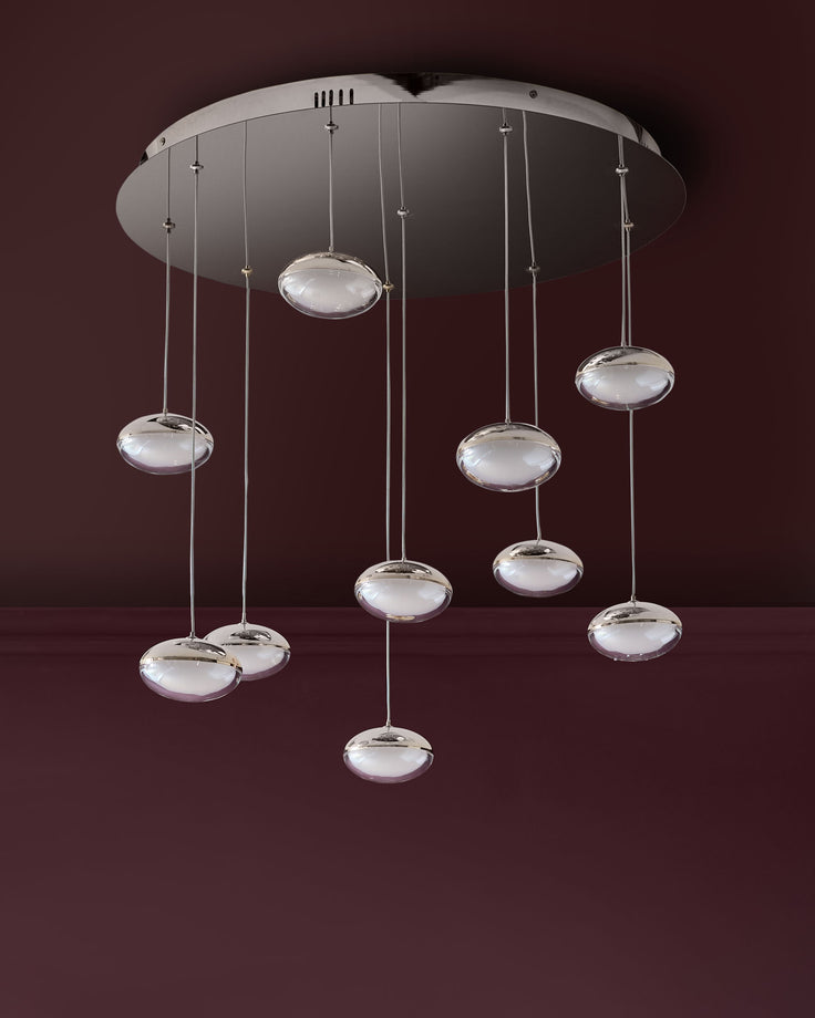 Nina 10-light pendant fixture with chrome finish and frosted glass disc shades suspended from ceiling canopy against burgundy background.
