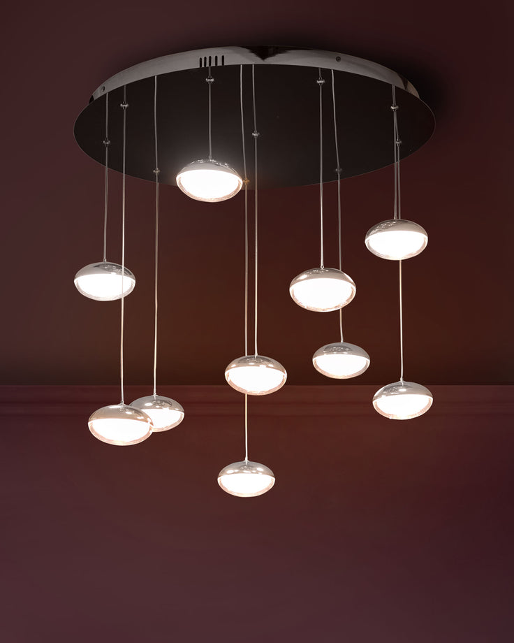 Nina 10-pendant light with round glass shades and chrome finish, suspended from a circular chrome canopy against a burgundy wall.