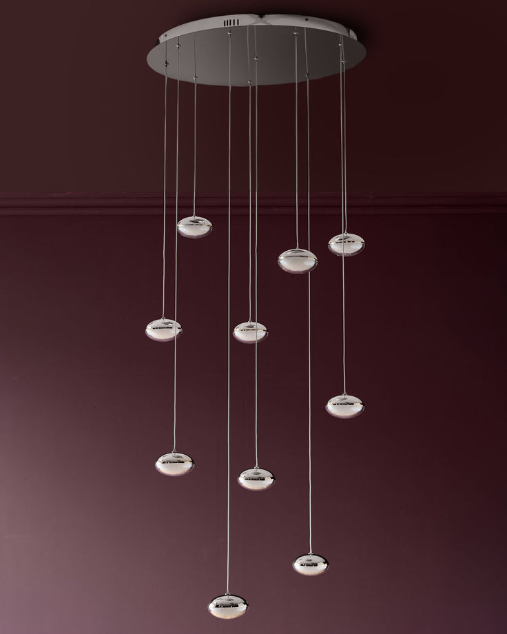 Nina 10-pendant light with chrome finish and frosted glass shades suspended from circular canopy against burgundy wall.