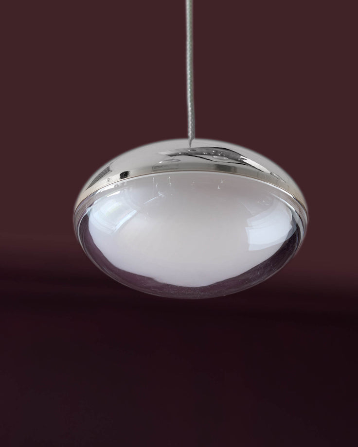 Nina 7 pendant light with frosted glass dome and polished chrome metal frame, suspended against burgundy background.
