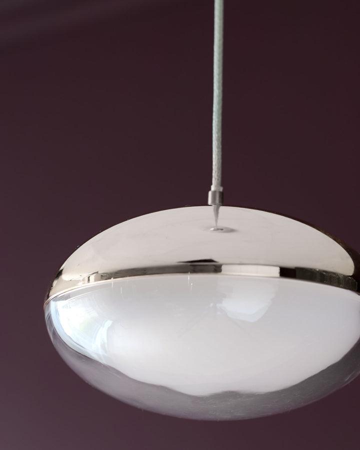 Nina single pendant light with frosted glass shade and polished chrome metal frame, suspended against purple background.