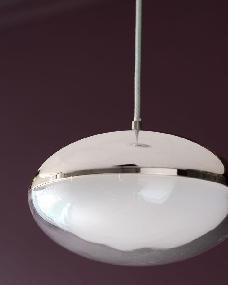 Nina single pendant light with frosted glass shade and polished chrome metal frame, suspended against purple background.