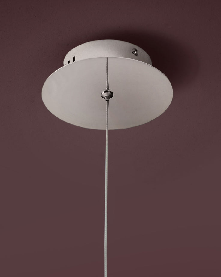 Nina single pendant light with frosted glass diffuser and polished chrome suspension cord against mauve wall.