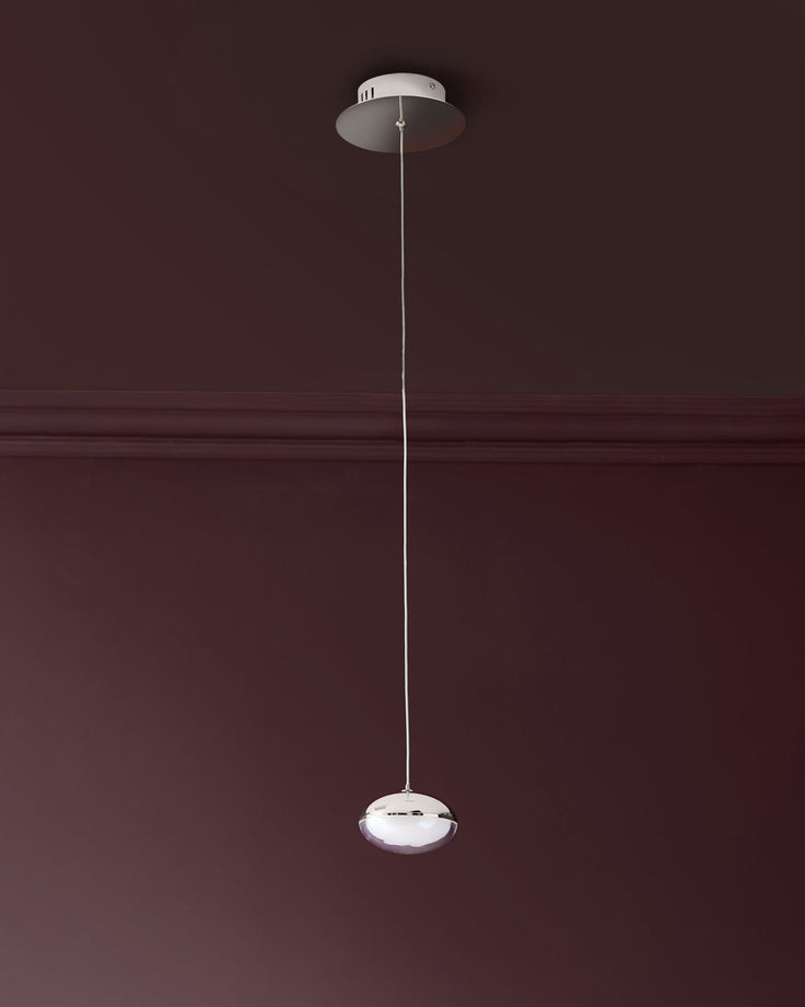 Nina single pendant light with chrome finish and frosted glass shade, suspended by thin wire from ceiling canopy against burgundy wall.