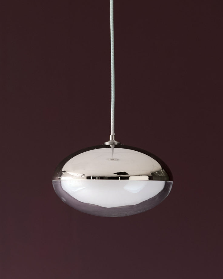 Nina single pendant light with polished chrome finish and frosted glass bowl shade, hanging against burgundy background.