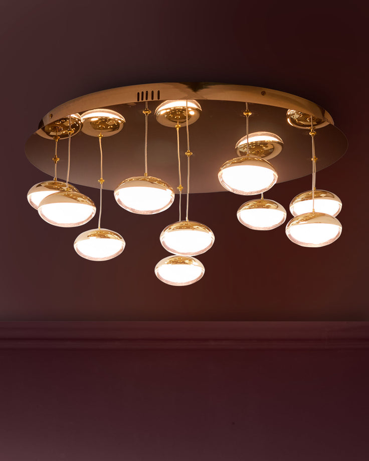 Nina 10-pendant light in soft gold finish with round glass shades, suspended from gold rods on circular ceiling mount.