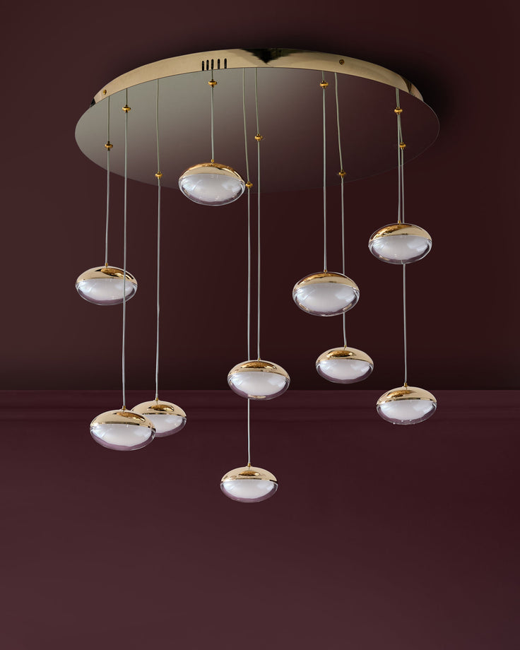 Nina 10-pendant light with soft gold finish and frosted glass dome shades suspended from a round ceiling canopy.