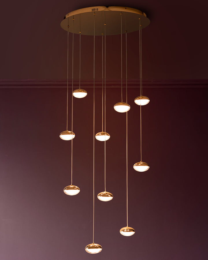 Nina 10-pendant light with soft gold finish and frosted glass shades, suspended at varying heights from circular ceiling plate.