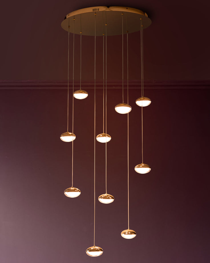 Nina 10-pendant light with soft gold finish and frosted glass shades, suspended at varying heights from circular ceiling plate.