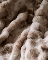 Nova throw blanket in natural tones, close-up showing soft, textured fabric with draped folds and layered appearance.