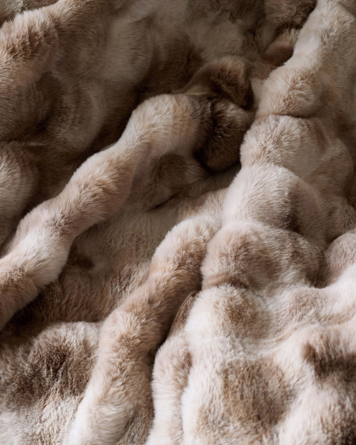Nova throw blanket in natural tones, close-up showing soft, textured fabric with draped folds and layered appearance.