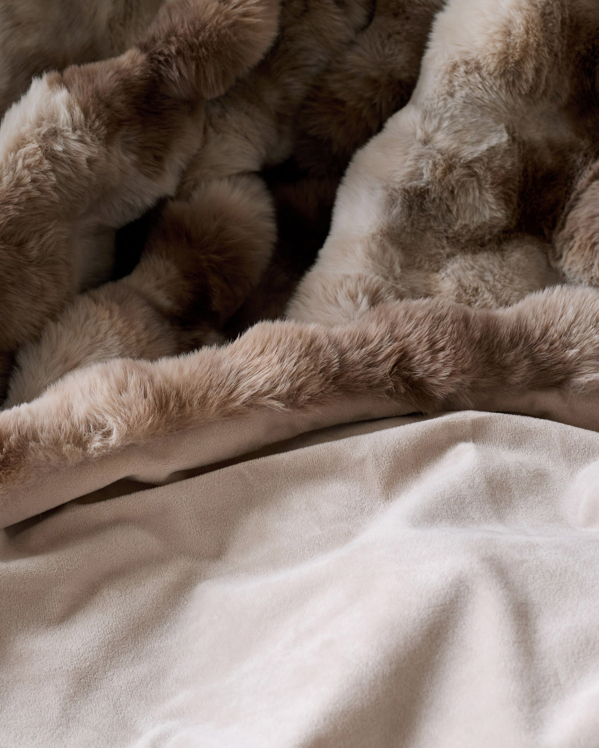 Nova throw blanket in natural color, draped and layered on neutral bedding, showing soft texture and neutral tones.