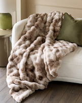 Nova throw blanket in natural color draped over cream armchair with green pillow.