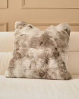 Nova Cushion Large in natural beige, featuring luxurious faux fur texture, displayed on a cream sofa against a paneled wall.
