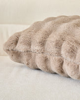 Large taupe cushion with gathered ruched texture and soft plush fabric, displayed at an angle on neutral background.